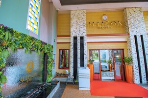 La entrada del Hotel Allison, con alfombra roja, puerta de vidrio y un letrero arriba.