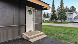 A single-story building with a white front door, a small porch, and a mailbox.