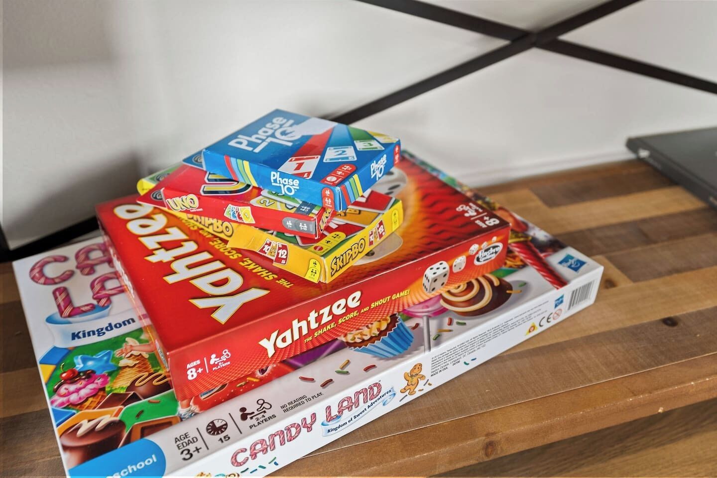 A stack of board games on a wooden surface.