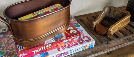 A copper pot on a wooden tray with a board game and a wooden brush.