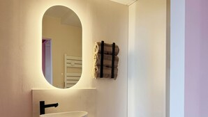Ein Badezimmer mit einem weißen Waschbecken, einem schwarzen Wasserhahn und einem Spiegel mit Beleuchtung darüber.