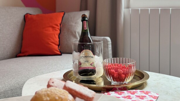 Ein Zimmer mit einer Couch, einem Tisch mit Speisen, einer Weinflasche und einer Wandverzierung.