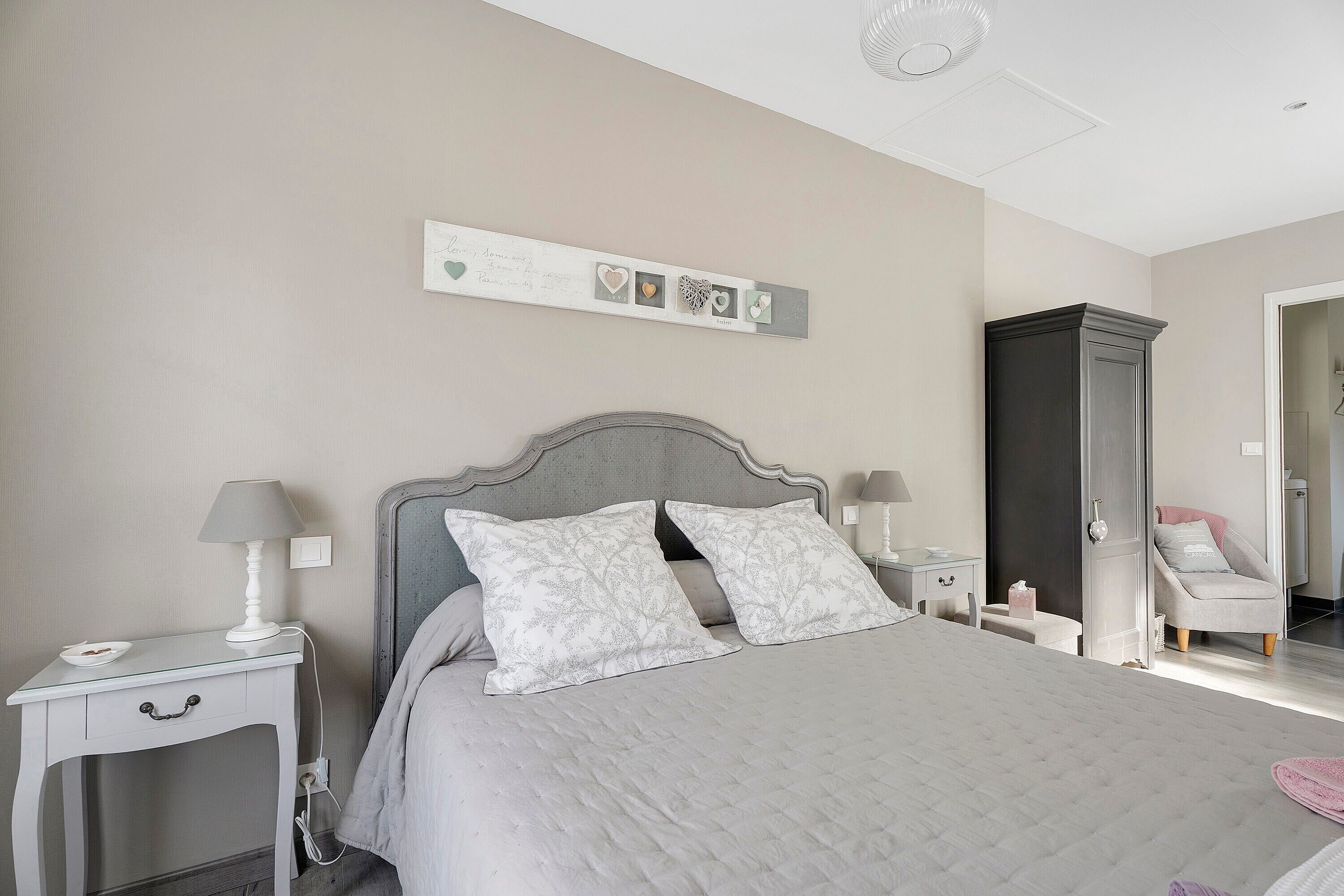 A bedroom with a bed, nightstands, a dresser, and a vanity with a mirror.