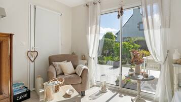 Ein gemütliches Wohnzimmer mit einer Couch, einem Couchtisch und Blick ins Freie.