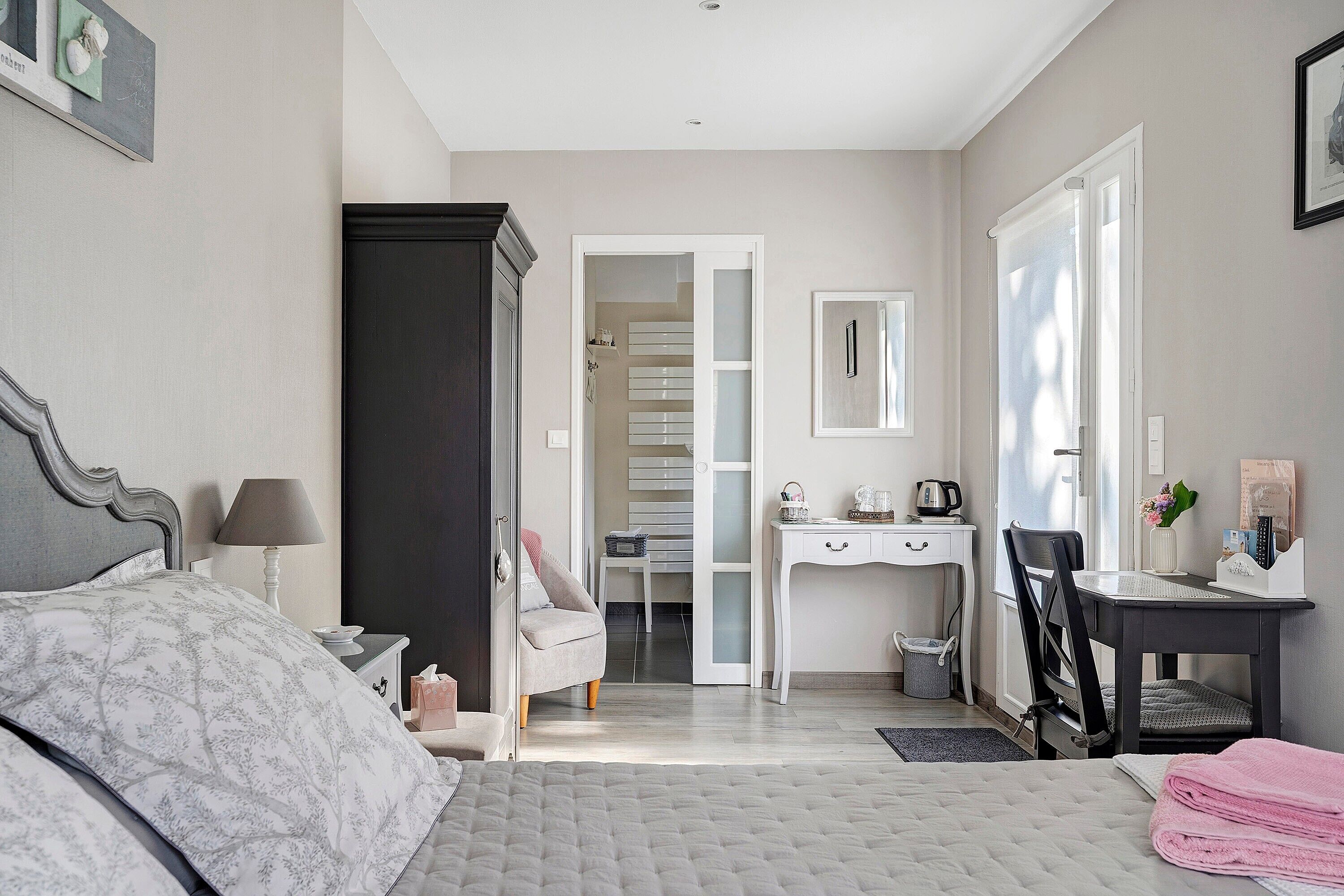 Una camera da letto con un letto, una scrivania, una sedia, un armadio e un bagno parzialmente visibile attraverso una porta aperta.