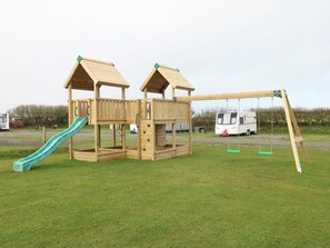 Eine Spielplatzkonstruktion aus Holz mit Rutsche und Schaukeln.