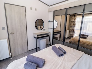 Ein Hotelzimmer mit Bett, Schreibtisch, Spiegel, Heizkörper und einem Fenster mit Vorhängen.