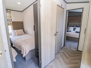 A bedroom with a bed, a wardrobe, and a mirror. - Stone Crab Lodge (Haverfordwest)