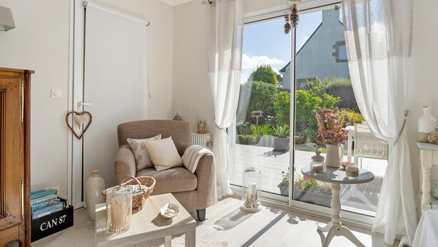 A cozy living room with a sofa, a coffee table, and a view of the outdoors. - Rêves d'Emeraude – Le Rêve du Pêcheur Guest Room (Cancale)