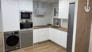 A compact kitchen with built-in appliances, a wooden countertop, and a white backsplash. - 4-Bedroom Beach Apartment in Ribeira | Ocean Views & Just Steps from the Beach (Ribeira)