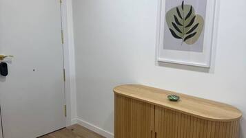 Une pièce avec une porte blanche, un meuble en bois et une œuvre d’art représentant une feuille, encadrée, accrochée au mur.