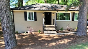 A single-story house with a front entrance, a small porch, and a front yard with trees and grass. - 3-bedroom house in soothing Atlanta with cool AC comfort (Atlanta)