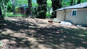 A residential area with a dirt yard, a small brick building, and a larger beige house. - 3-bedroom house in soothing Atlanta with cool AC comfort (Atlanta)