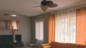 A living room with a sofa, a chair, a coffee table, a ceiling fan, and a window with curtains. - 3-bedroom house in soothing Atlanta with cool AC comfort (Atlanta)