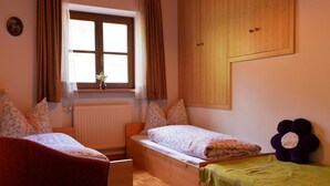 A bedroom with two beds, a window with curtains, a radiator, and a wooden wardrobe. - Apartment "Wohnung Rosengarten Wieserhof" with Mountain View, Shared Garden & Wi-Fi (Aica di Sopra)