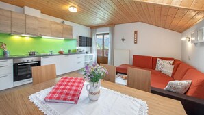 A modern kitchen with wooden cabinets, a green backsplash, and a dining area with a table set for two. - Apartment "Wohnung Rosengarten Wieserhof" with Mountain View, Shared Garden & Wi-Fi (Aica di Sopra)