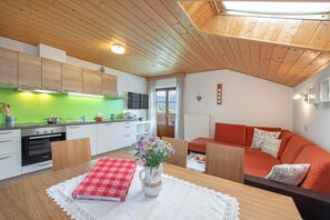 Eine moderne Küche mit Holdekor-Schränken, einer grünen Rückwand und einem Essbereich mit Tisch für zwei Personen.