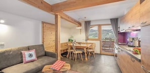 Ein gemütliches Zimmer mit Holzboden, einem Essbereich mit Tisch und Stühlen sowie einer Küche mit Holzausstattung.