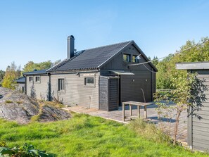 A single-story house with a dark roof and siding, a chimney, and a small deck area. - 4 Star Holiday Home in Trollhattan (Trollhattan)