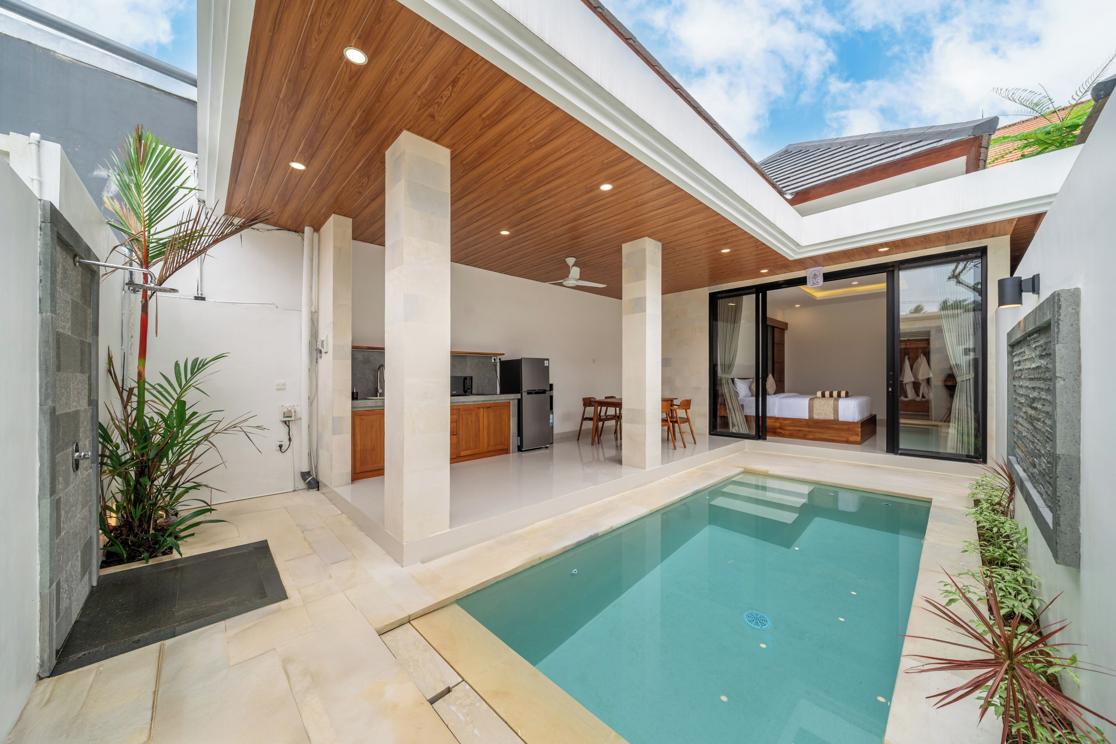 Ett modernt hus med en swimmingpool, ett kök och ett vardagsrum med en soffa och ett matbord.