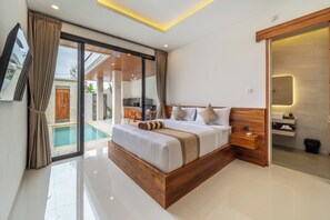 Un dormitorio moderno con una cama grande, cabecera de madera, mesita de noche integrada y baño con tocador de madera.