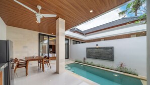 Una cocina moderna con refrigerador empotrado, mesa de madera y sillas.