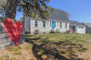 A single-story house with a front porch, a blue door, and a small attached garage. - Spacious, 4-bedroom, Dogs ok, Minutes from Beaches! (Harwich)