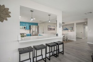 Eine moderne Küche mit einer zentralen Kochinsel, Barhocker und einem Essbereich mit Tisch und Stühlen.