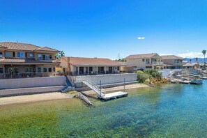 Ein Haus am Wasser mit freiem Blick auf das Gewässer, einem Steg und mehreren Häusern mit Balkonen.