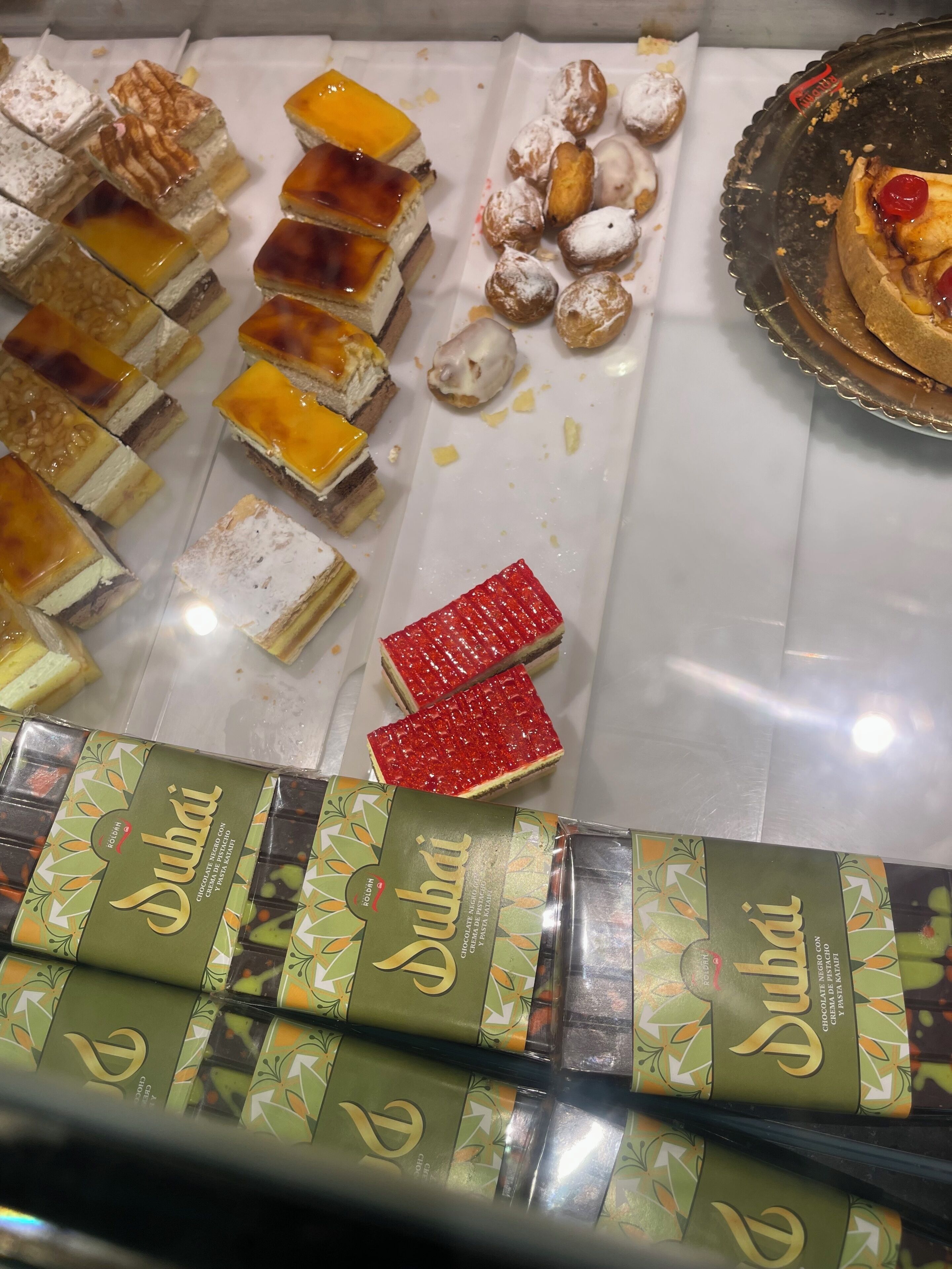 A variety of desserts including cakes and pastries, with a focus on a chocolate product labeled 'Dubai.'