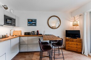 A compact kitchen with a microwave, coffee maker, and wooden table. - Le Josephine Apartment: Beachside Location with Terrace and Garden (Arcachon)
