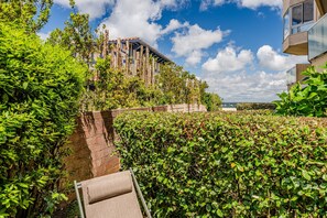 A garden with a brick wall, a wooden bench, and a building with a balcony. - Le Josephine Apartment: Beachside Location with Terrace and Garden (Arcachon)