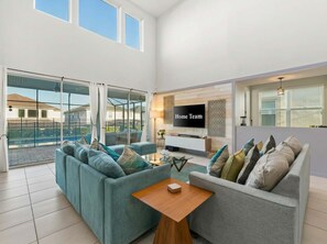A modern living room with a sofa set, a coffee table, and a flat-screen TV mounted on the wall. - 6 mins to Disney • Game/Themed Rooms • Pool (Kissimmee)
