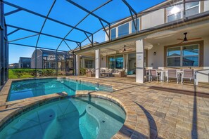 A swimming pool with a glass enclosure, outdoor seating, and a patio area. - 6 mins to Disney • Game/Themed Rooms • Pool (Kissimmee)
