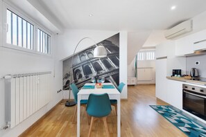A modern kitchen with a dining area, a radiator, and a large window. - Penthouse Between Sky and Sea with Panoramic Terrace - Lido Di Ostia (Lido di Ostia)