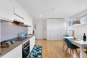 Una cocina moderna con armarios blancos, encimera de madera y un comedor con mesa y sillas.