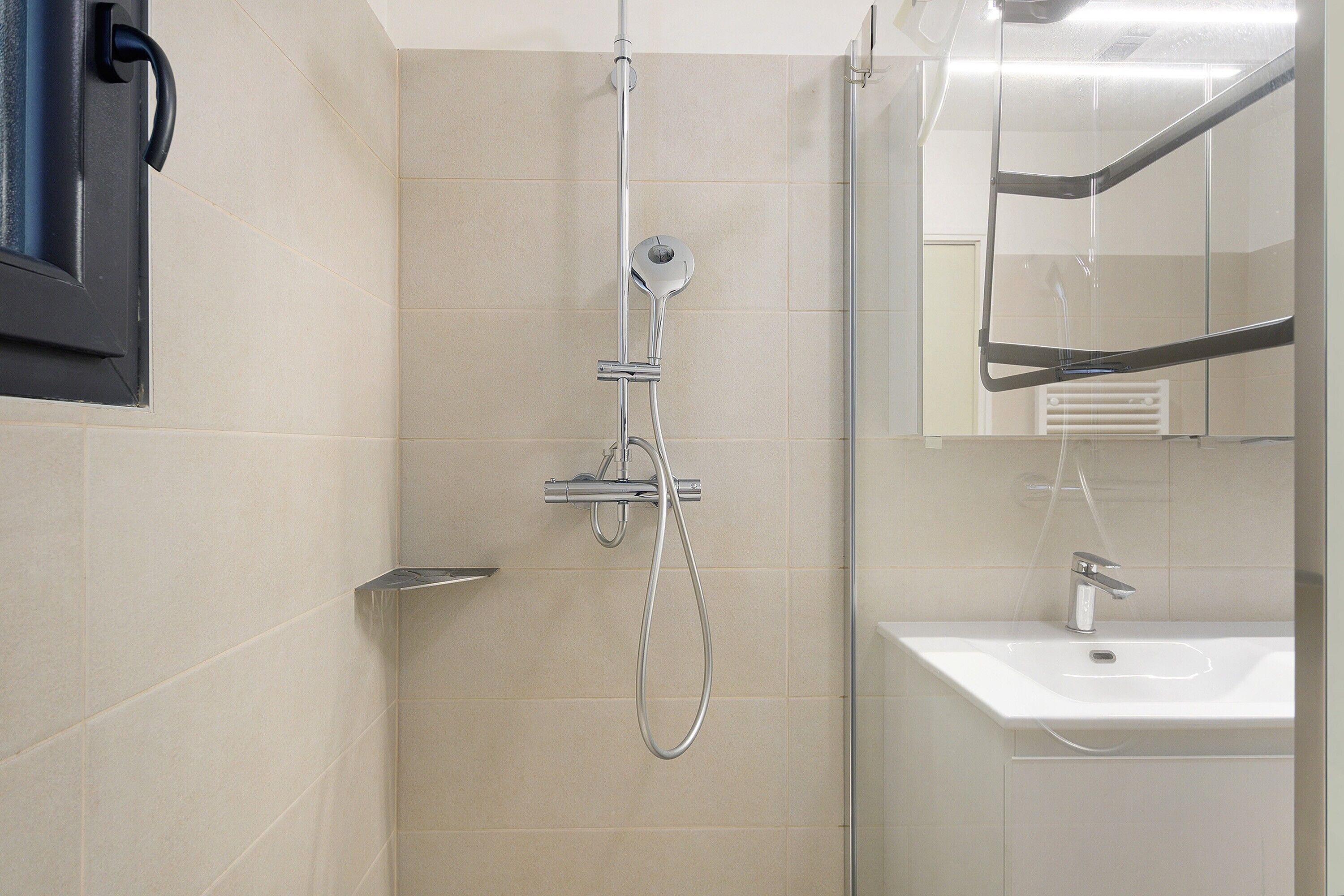 Une salle de bain avec une douche, un lavabo et un miroir.