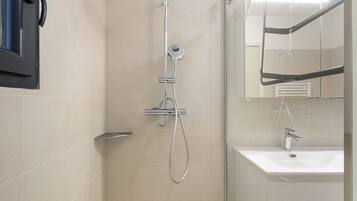 Une salle de bain avec une douche, un lavabo et un miroir.