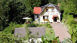 Ein Haus mit einem geneigten Dach, einer Veranda und einem Weg zum Eingang.