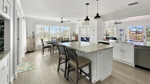 A spacious kitchen with a large island, pendant lighting, and a view to the outside. - Saltwater Pool & Spa Villa on a Gulf-Access Canal (Englewood)