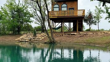 A wooden decked structure with a view of a lake, surrounded by trees.