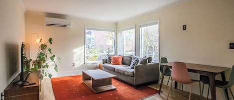 A modern living room with a sofa, coffee table, and dining area.