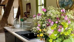 Eine Küchenarbeitsplatte mit einer Blumenvase, einer Zitronenschale und einem Fenster mit Blick ins Freie.