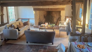 Ein gemütliches Wohnzimmer mit Kamin, einer Couch, einem Couchtisch und einem Essbereich mit Tisch für zwei Personen.