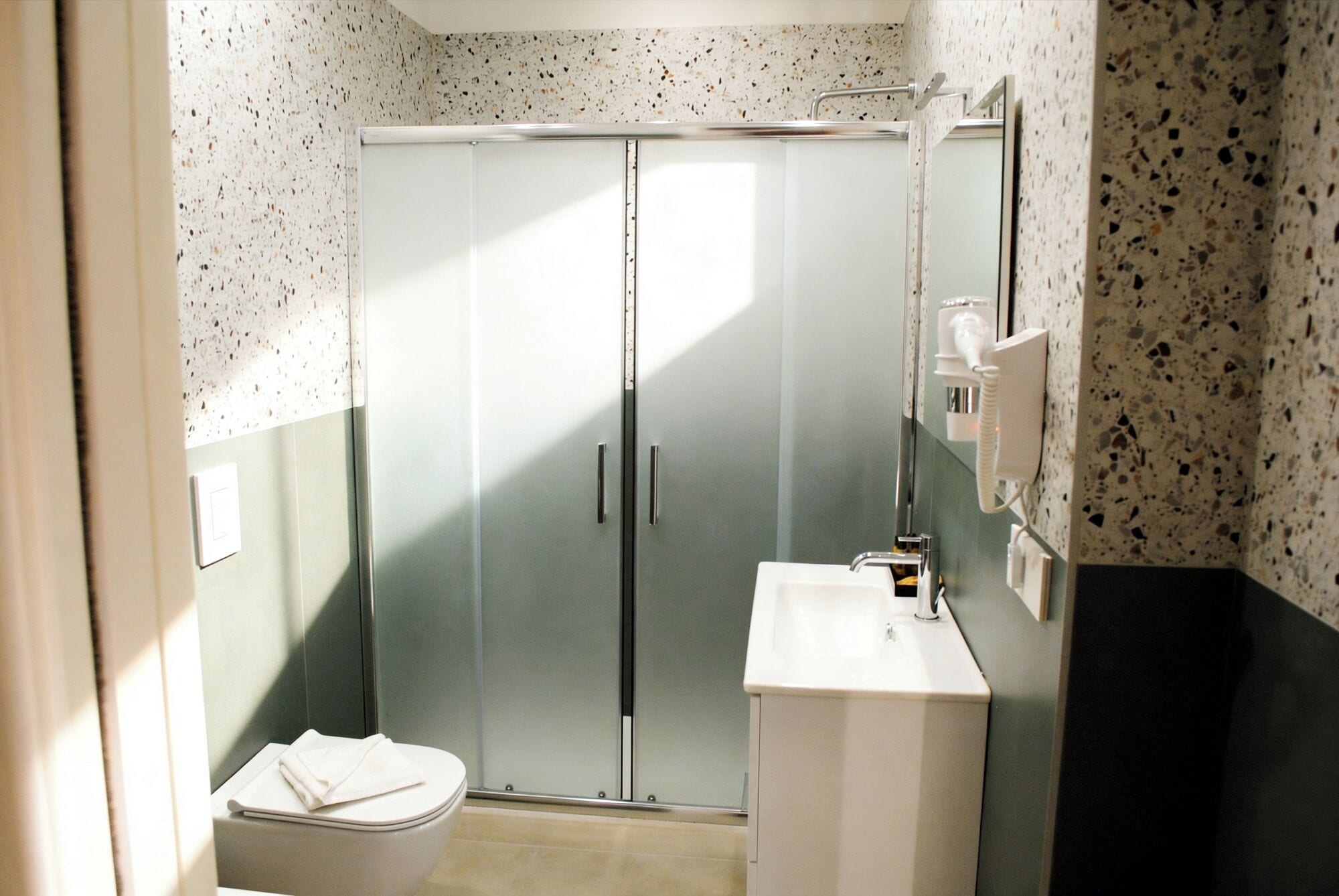 A bathroom with a glass-enclosed shower, a white sink, and a toilet.
