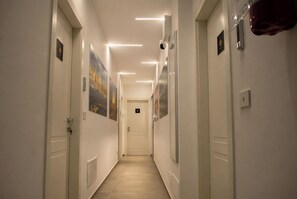 Un pasillo con puertas, cuadros enmarcados e iluminación empotrada.