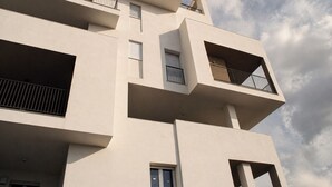 Un edificio de varios pisos con balcones, ventanas y un cielo despejado.