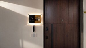 Entrada a una habitación de hotel con puerta de madera, lector de llave digital y cartel que indica los tipos de habitación.