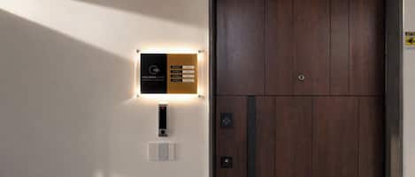 A hotel room entrance with a wooden door, a digital keycard reader, and a sign indicating room types.