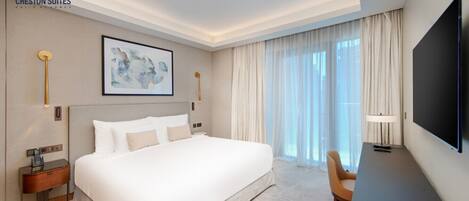 A hotel room with a large bed, a desk, a TV, and a painting on the wall.